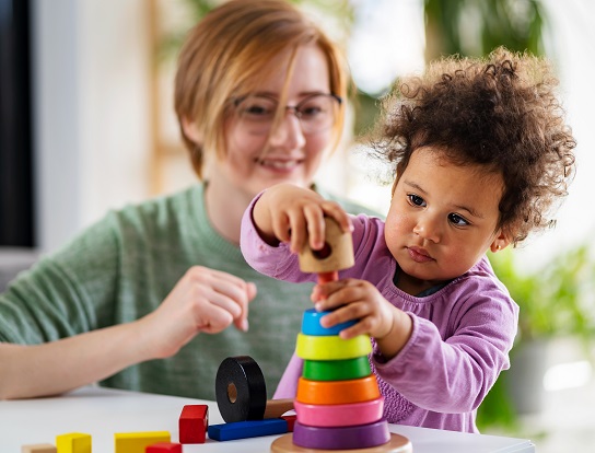 Mother looking at a child playing with an educational didactic t