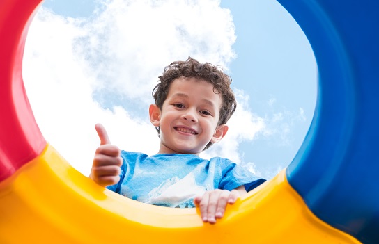 kid boy thumbs up and having fun to play on children's climbing