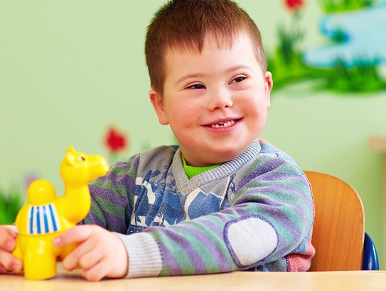 cute kid with down's syndrome playing in kindergarten