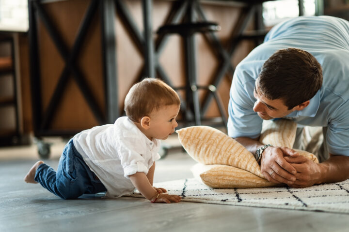 Small boy crawling while spending time with his father at home.