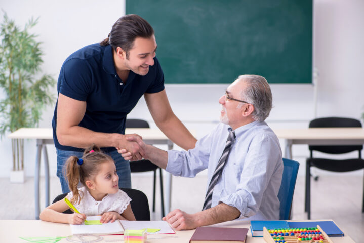 Young parent, old male teacher and little girl in the classroom