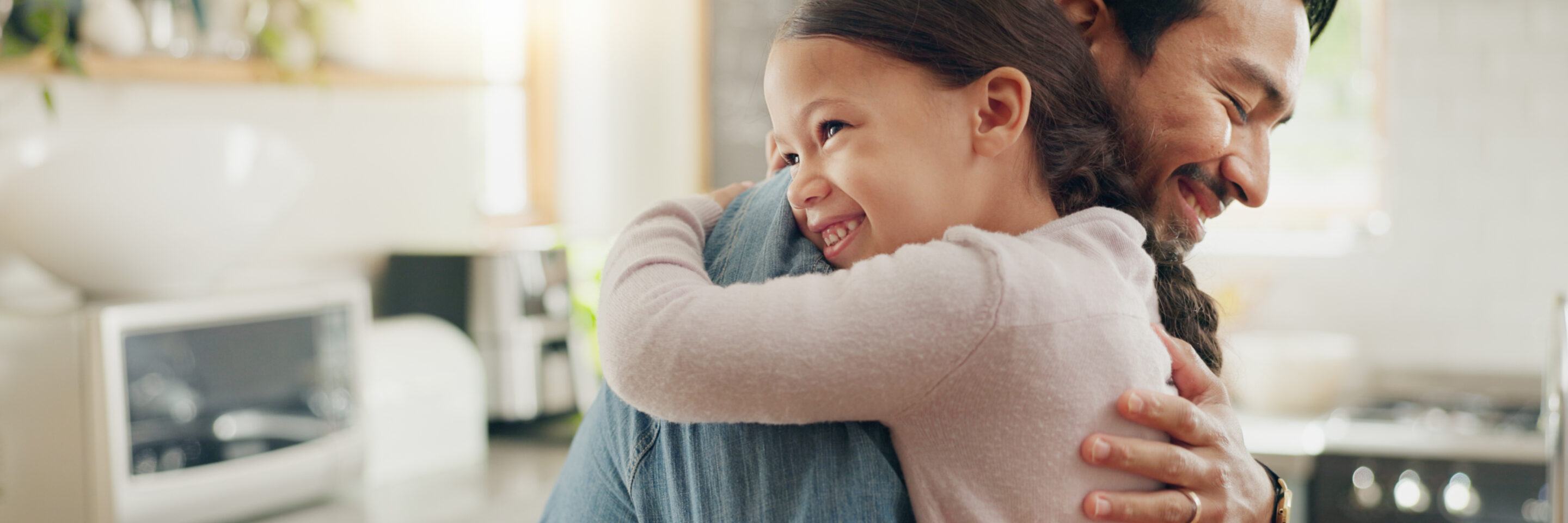 Family, father and daughter hug in the kitchen for love, trust or bonding together in their home. Kids, smile and safety with a happy young man embracing his adorable girl child in their house