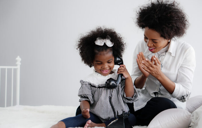 african american girl child enjoy playing telephone with her mot
