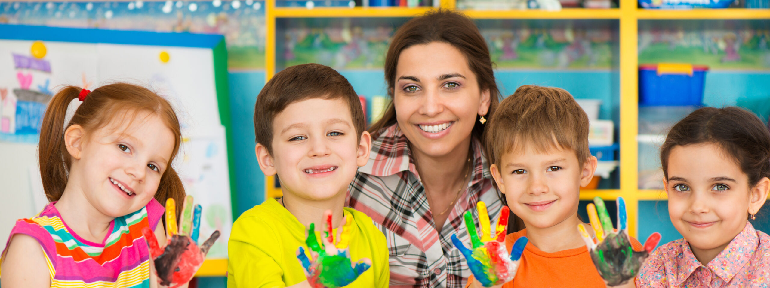 Cute little children drawing with teacher at preschool class