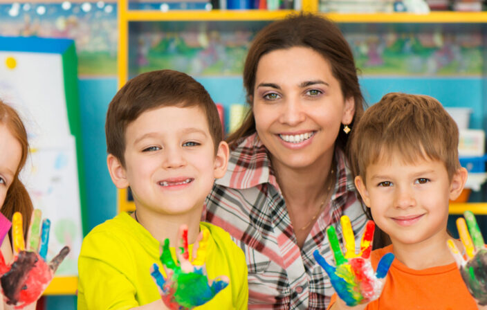 Cute little children drawing with teacher at preschool class