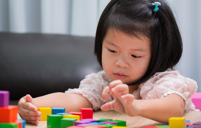 Child play with colorful wooden blocks on table. Concept is lear